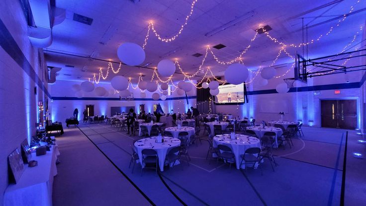 a large room with tables and chairs covered in white tablecloths is lit by blue lights