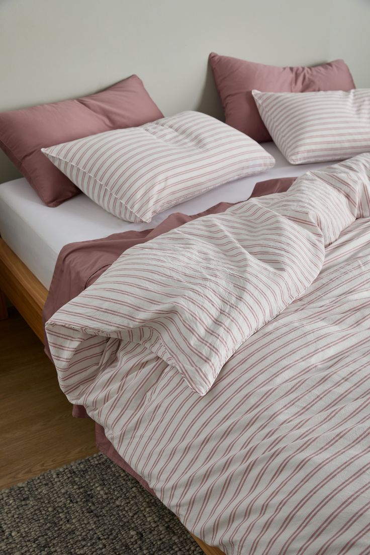 an unmade bed with pink and white striped sheets