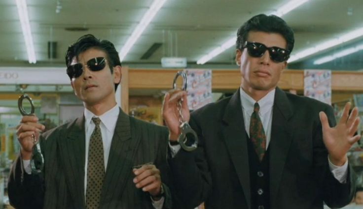 two men in suits and sunglasses holding up some kind of pair of eyeglasses