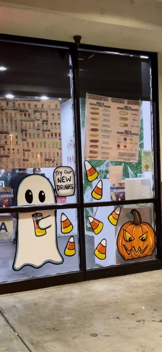 a store front window decorated for halloween with ghost, pumpkins and candy corn on it