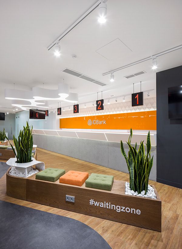 an office lobby with planters and televisions on the wall above it, along with wooden flooring