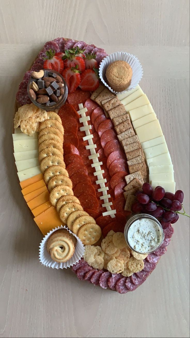 a football shaped platter with cheese, crackers and meats