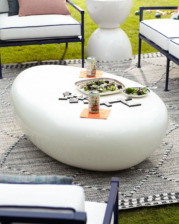 a white coffee table sitting on top of a grass covered field next to two chairs