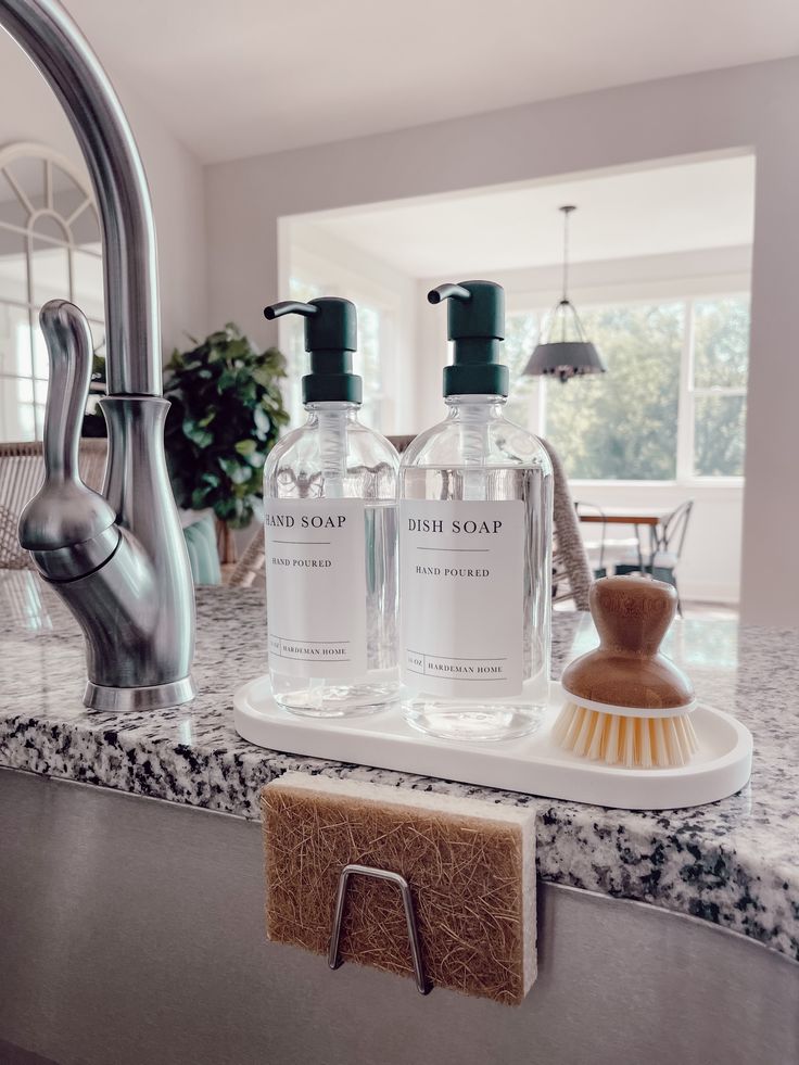 a kitchen sink with two bottles of hand soap and a scrubber