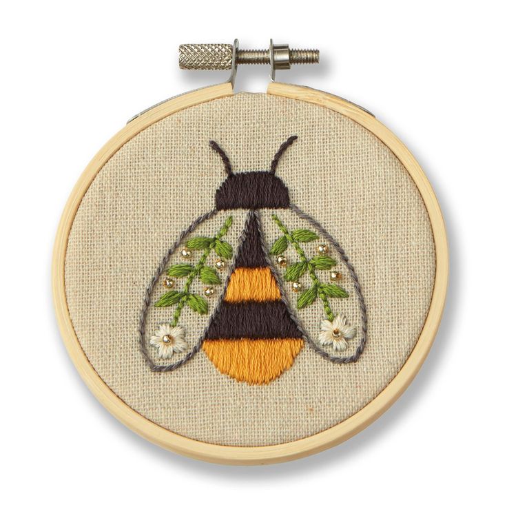 an embroidered bee with flowers and leaves on it's back, sitting in front of a white background