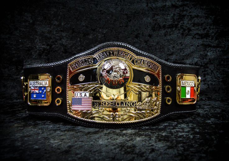 a gold and black wrestling belt with an american flag on the side, in front of a dark background