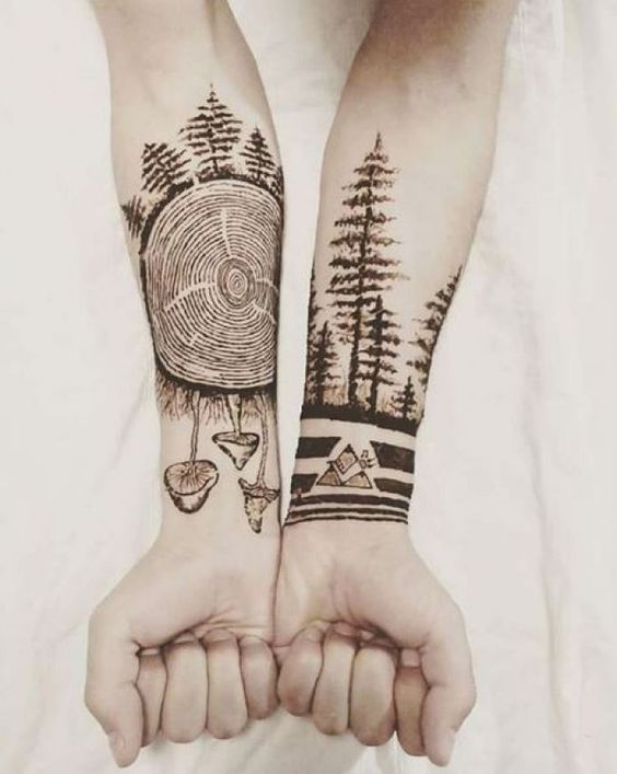 two people with tattoos on their arms holding each other's hands in front of the camera