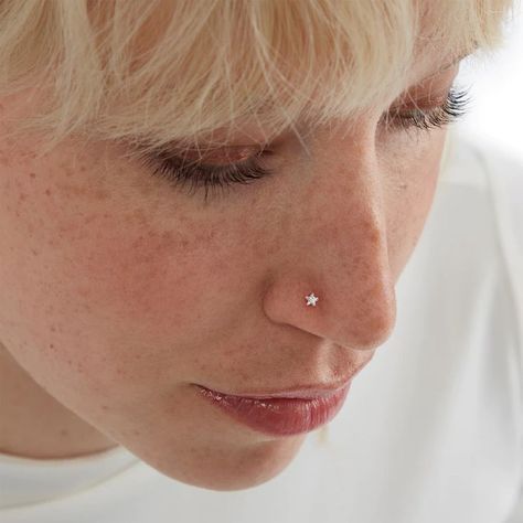 a close up of a person with a nose piercing in their left ear and wearing a white t - shirt