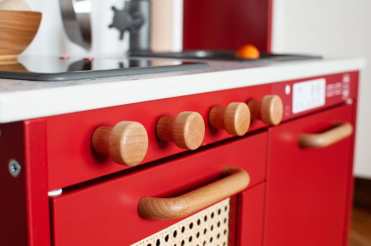 a red stove top oven sitting inside of a kitchen next to a wooden countertop