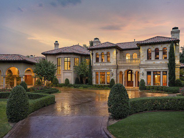 a large house with lots of windows and bushes in front of it at sunset or dawn