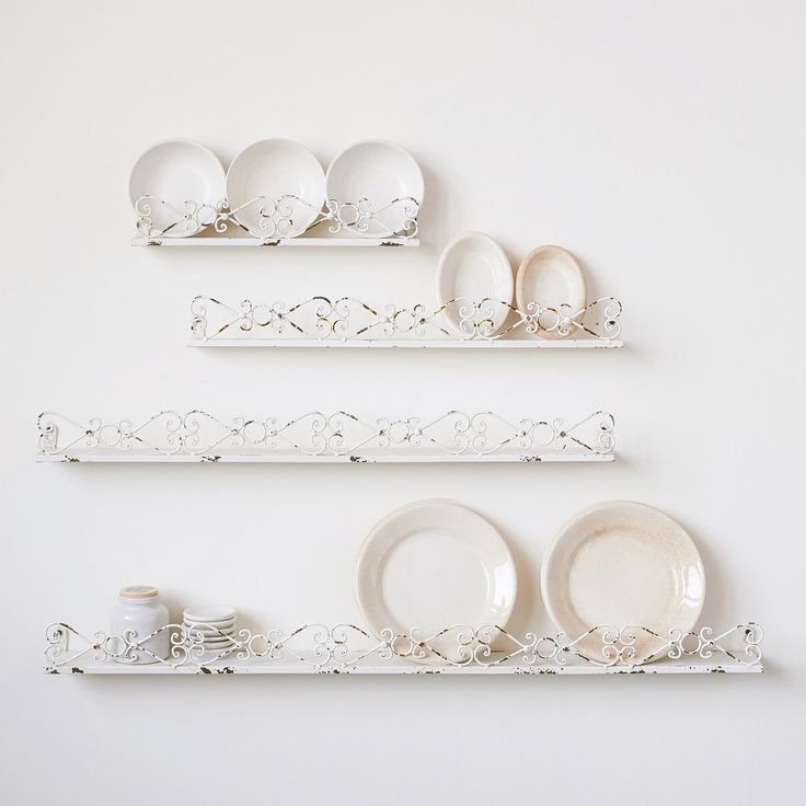 three white shelves with plates and dishes on them