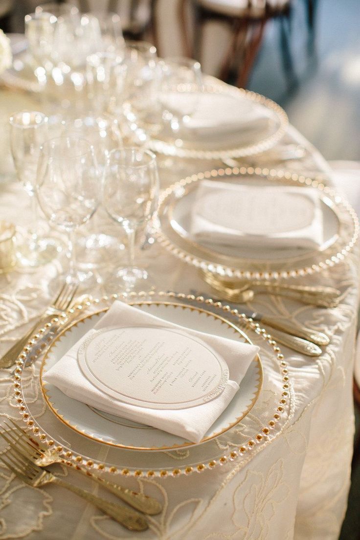 the table is set with white and gold place settings