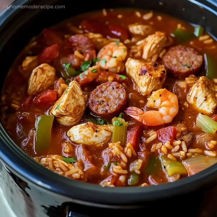 a close up of a bowl of soup with shrimp, sausage and rice in it