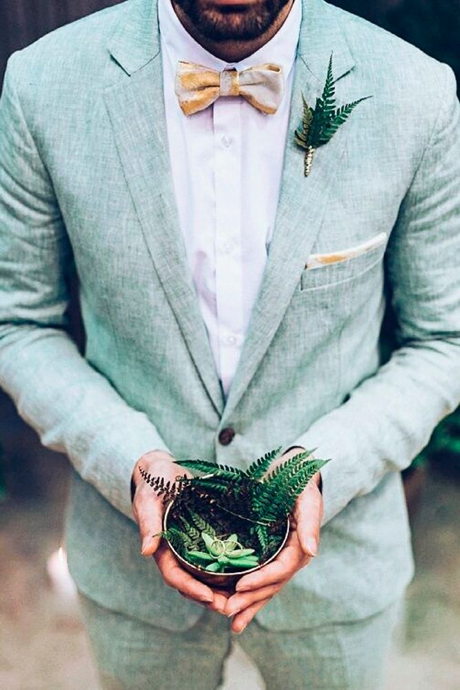 a man in a suit and bow tie holding a potted plant