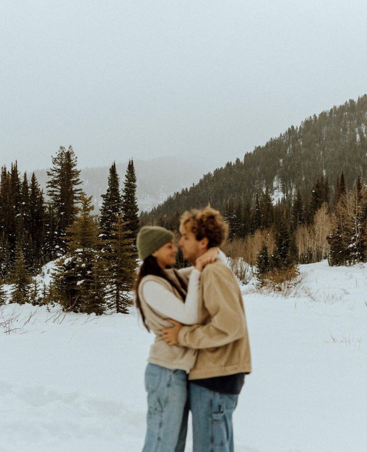 two people standing in the snow kissing each other