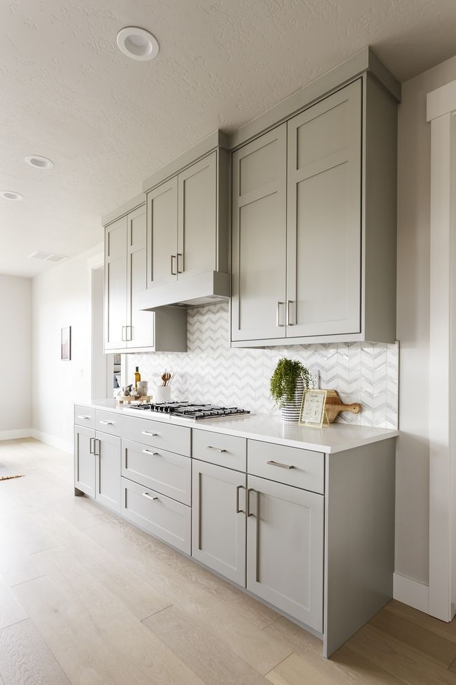 a kitchen with gray cabinets and white counter tops