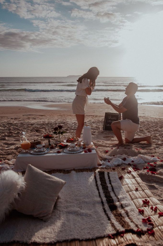 two people are sitting on the beach having a picnic