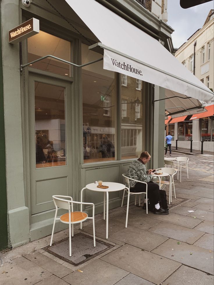 a man sitting at a table outside of a restaurant