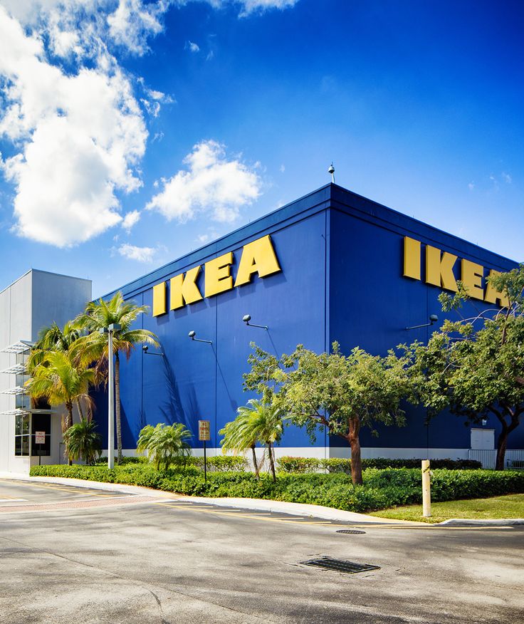 an ikea store with palm trees in the foreground and blue sky behind it