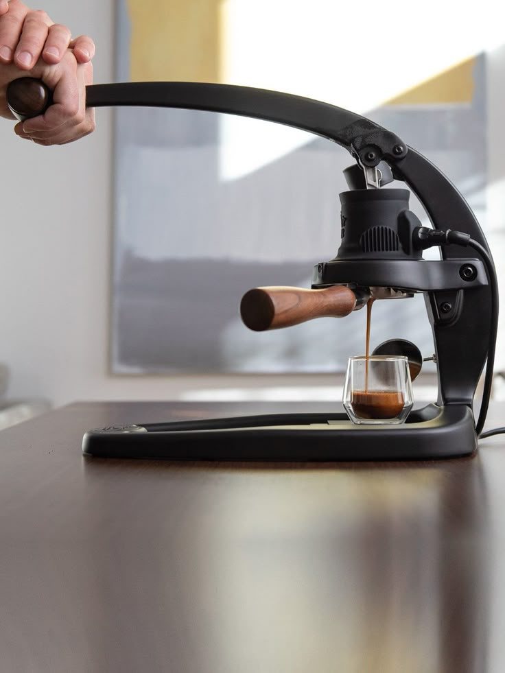 a person is pouring coffee into a cup on a table with a tabletop in front of them