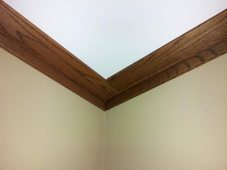 the corner of a bathroom with a toilet and wooden trim on the wall above it