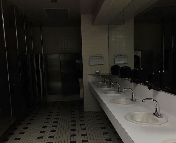 a row of sinks in a public restroom with black and white tiles on the floor