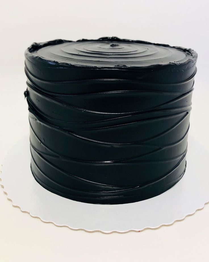 a black cake is sitting on a white plate