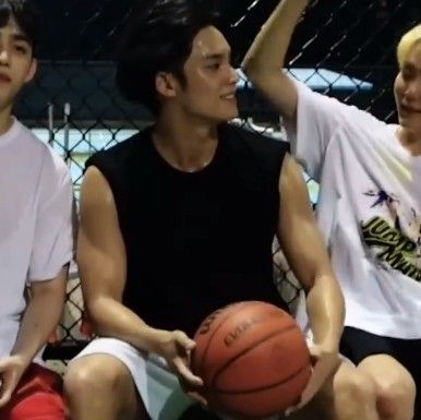 three young men sitting next to each other holding a basketball