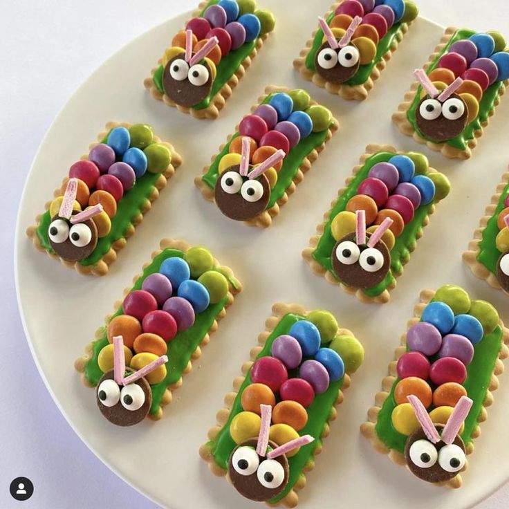 decorated cookies on a white plate with eyes and ears in the shape of bugs, carrots and grass