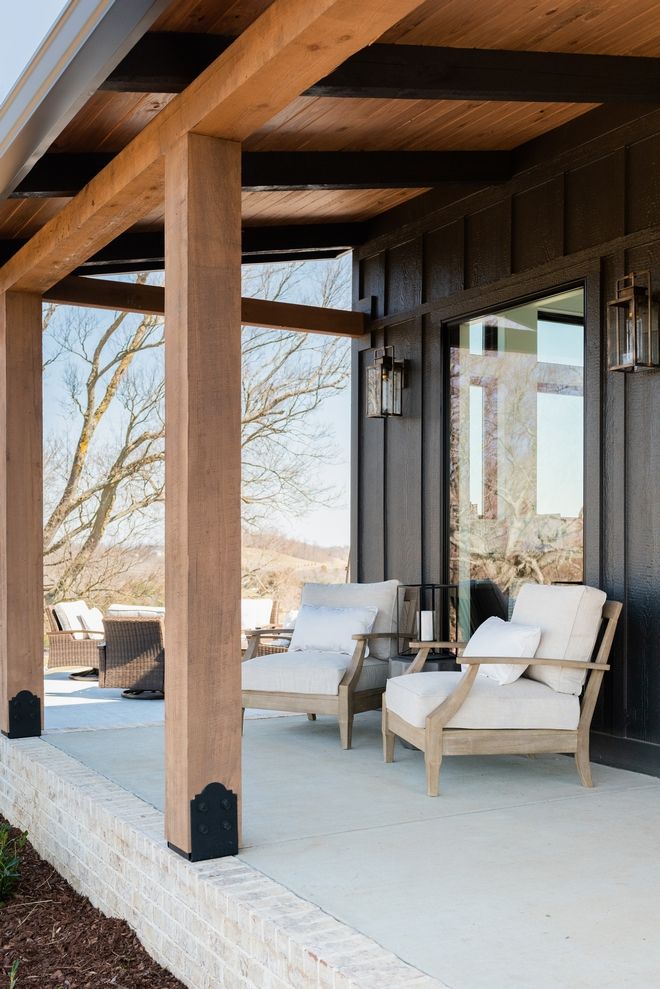 an outdoor covered patio with two chairs and a table on the other side of it