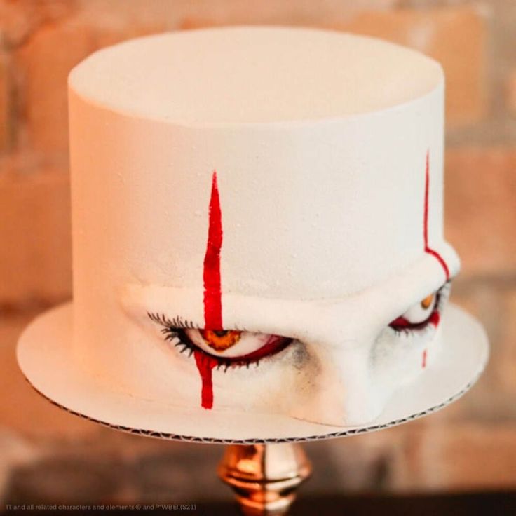 a close up of a white cake with red paint on it and an evil eye