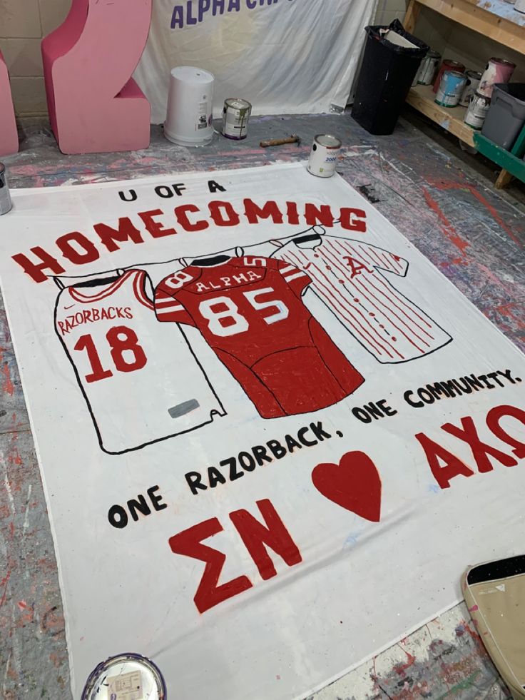 a baseball jersey is being made on the floor in front of a sign that says, home coming