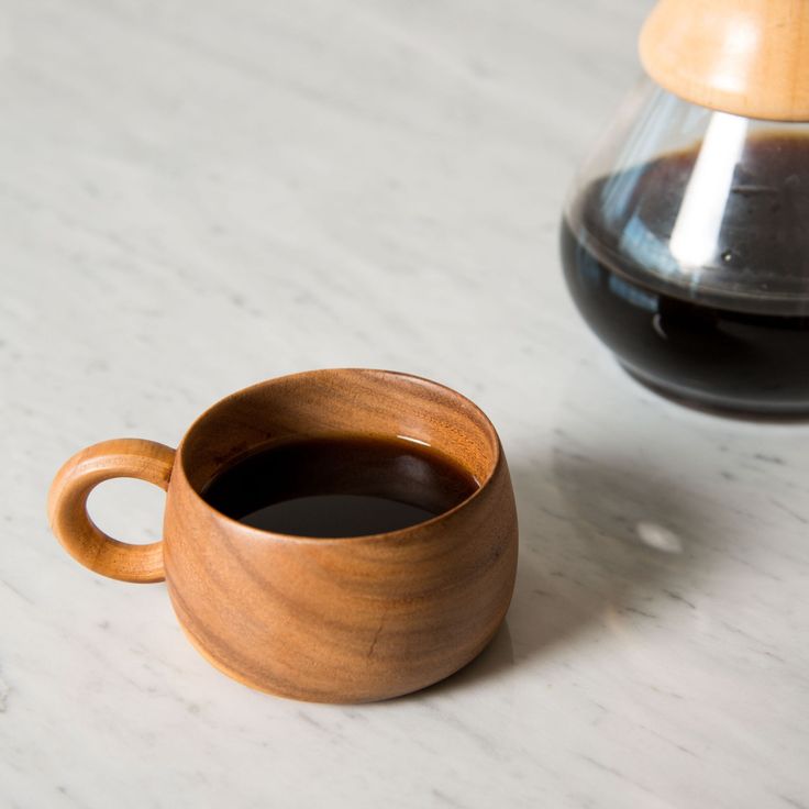 a cup of coffee sitting next to an espresso machine on a counter top