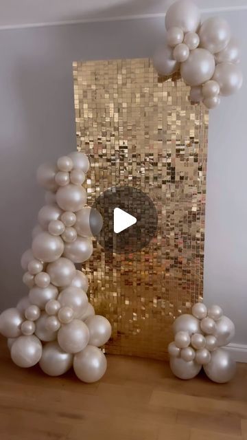 balloons are floating in the air next to a wall with gold and white tiles on it