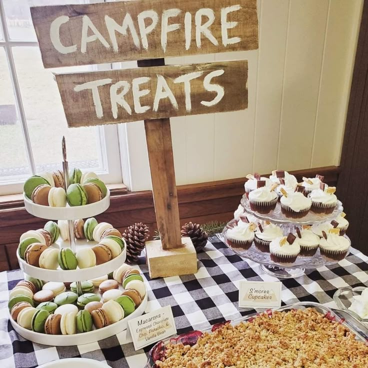 a table topped with lots of cupcakes next to a sign that says campfire treats