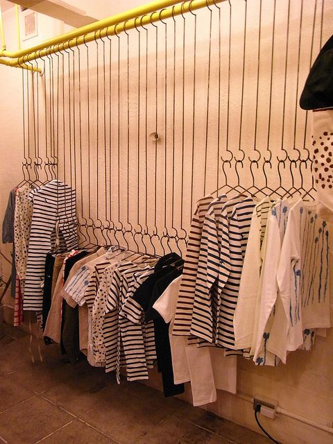 there are many shirts hanging on the rack in this room and one is black and white