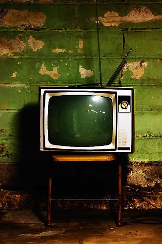 an old tv sitting on top of a wooden chair in front of a green wall