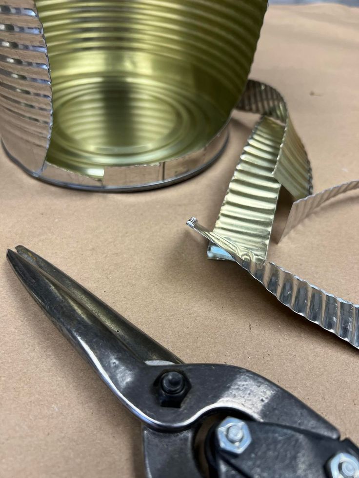 some scissors are sitting on a table next to a tin can and other metal items