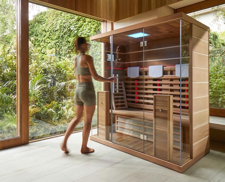 a woman is standing in front of a saunat with glass doors and shelves