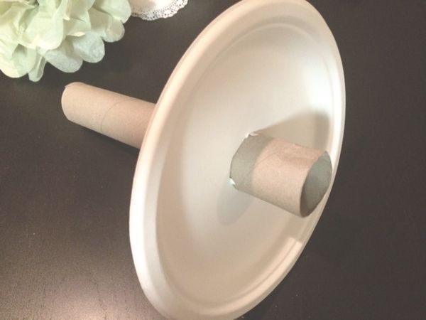 a toilet paper roll is sitting on top of a white bowl next to a flower