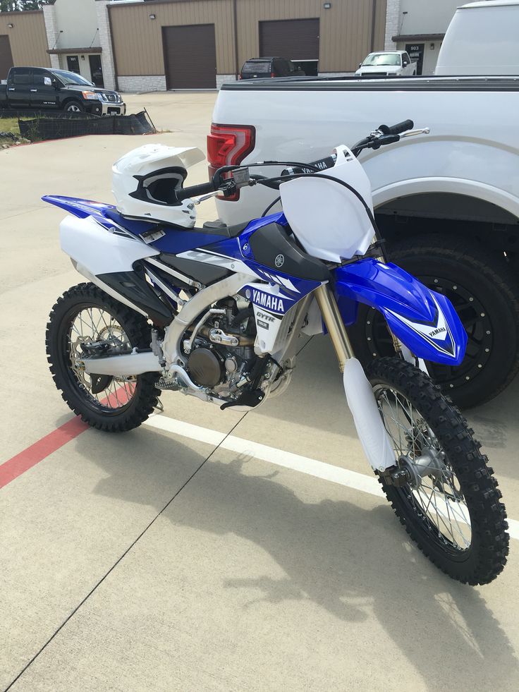 a blue and white dirt bike parked next to a truck