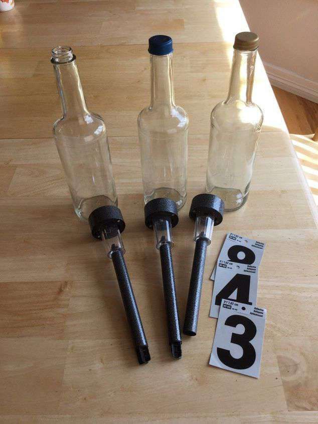 three empty glass bottles sitting on top of a wooden table next to two corkscrews