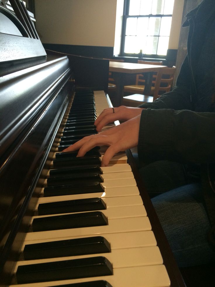 a person sitting at a piano with their hands on the keys