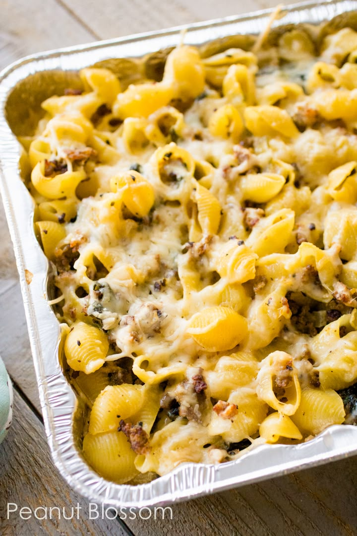 a casserole dish filled with pasta and meat in a metal pan on top of a wooden table