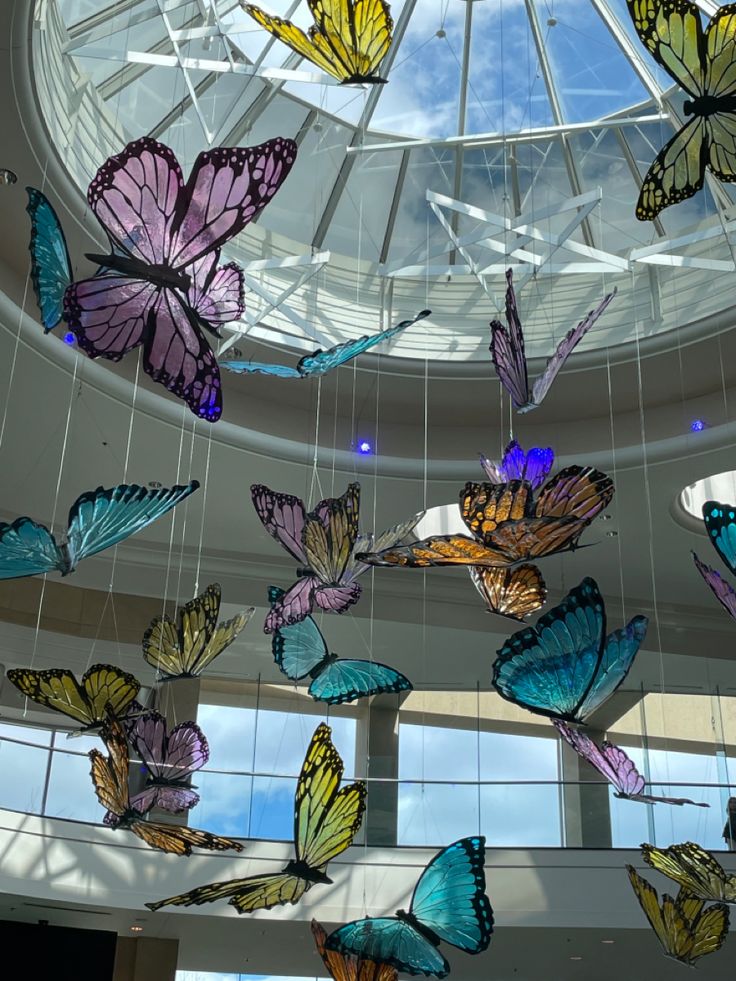 many butterflies are hanging from the ceiling in a circular room with large windows and a skylight