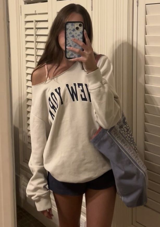 a woman taking a selfie in front of a mirror wearing a new york sweatshirt