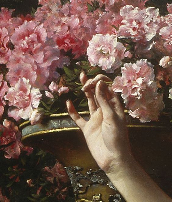 a person's hand reaching for pink flowers in a vase