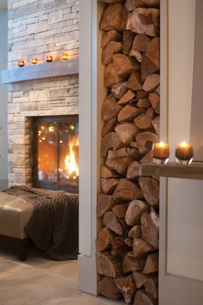 a fireplace with logs stacked on it and candles lit in front of the fire place