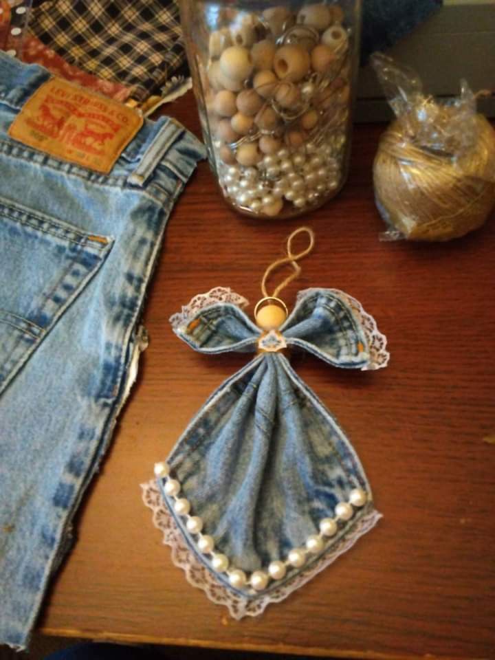 a pair of jean pants and some other items are on a table next to a jar full of beads