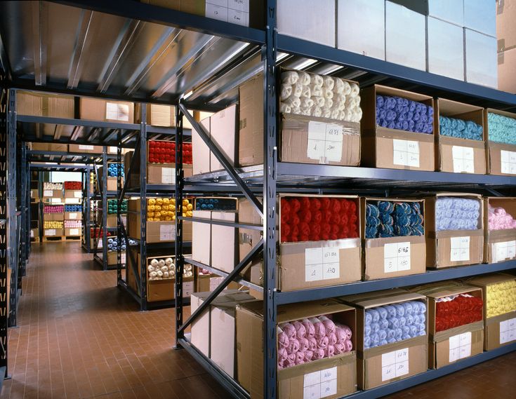 shelves filled with lots of different types of yarn and other items in bins on metal racks